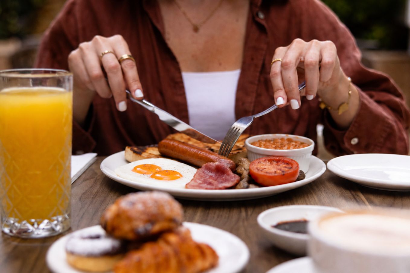 A breakfast setting with eggs, sausages, tomatoes, and a glass of orange juice.