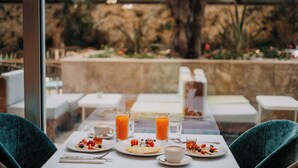 Uma mesa posta para dois, com pratos de comida, copos de suco de laranja e uma xícara de café.