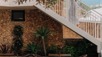 A woman on a staircase with a view of a stone wall and outdoor seating area.