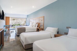 A hotel room with two beds, a desk, and a view of buildings.