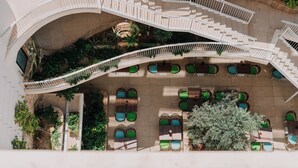 A multi-level outdoor terrace with curved staircases, green seating areas, and planters. - Reef Hotel & Spa (Marsalforn)
