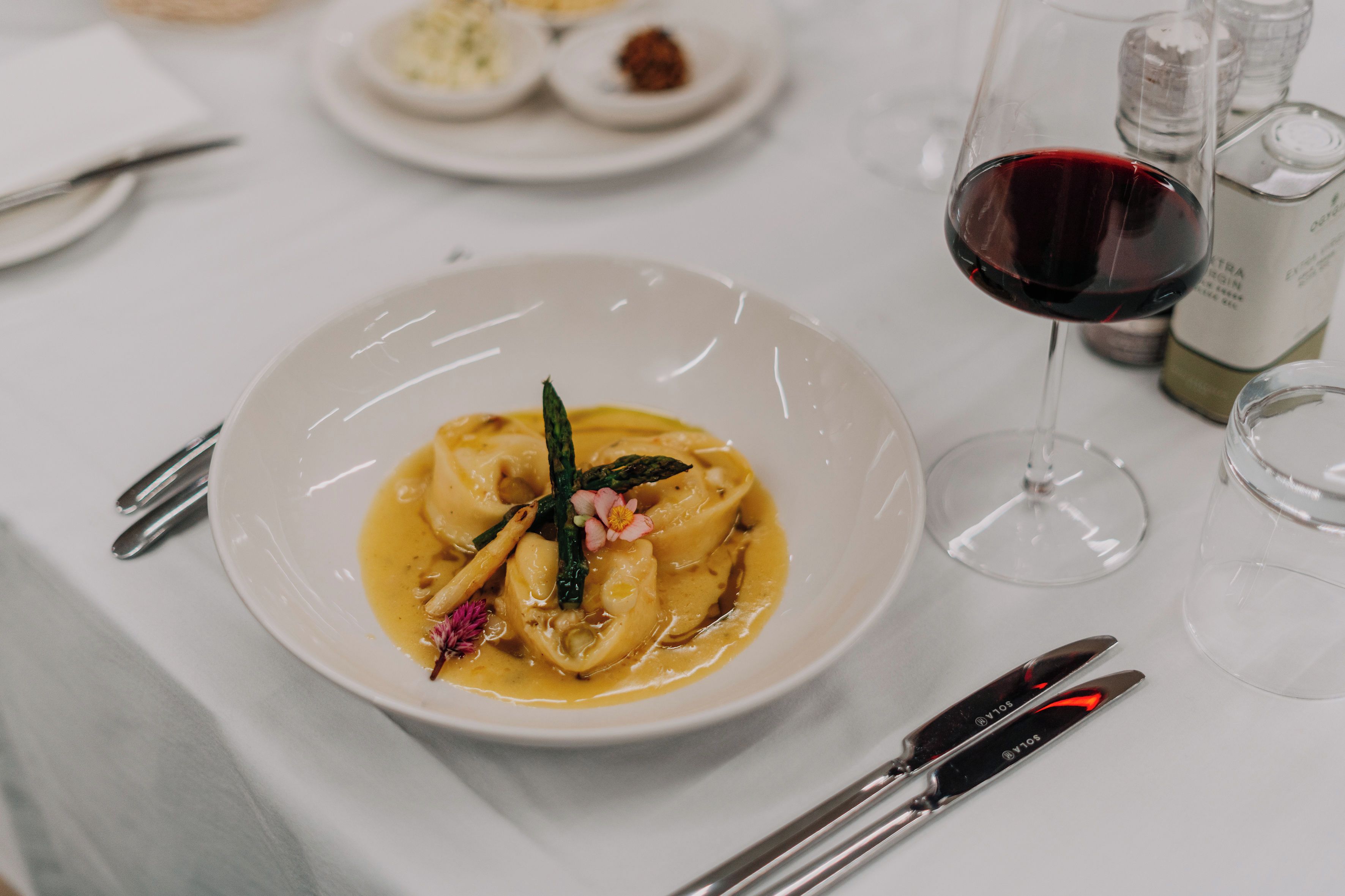A dining table with a plate of food, a wine glass, and cutlery.