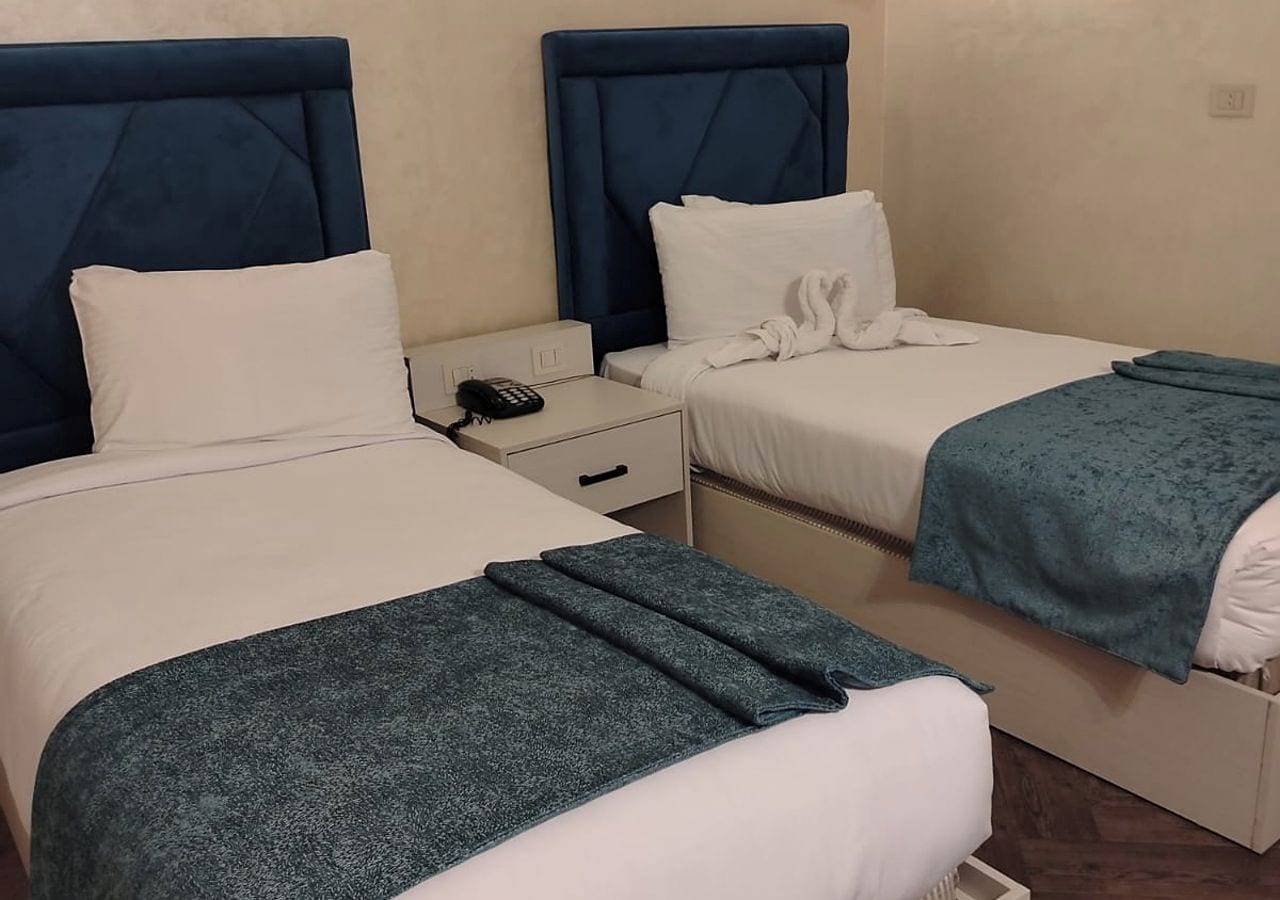 Une chambre d’hôtel avec deux lits, chacun doté d’une tête de lit, d’une table de chevet et d’un téléphone.