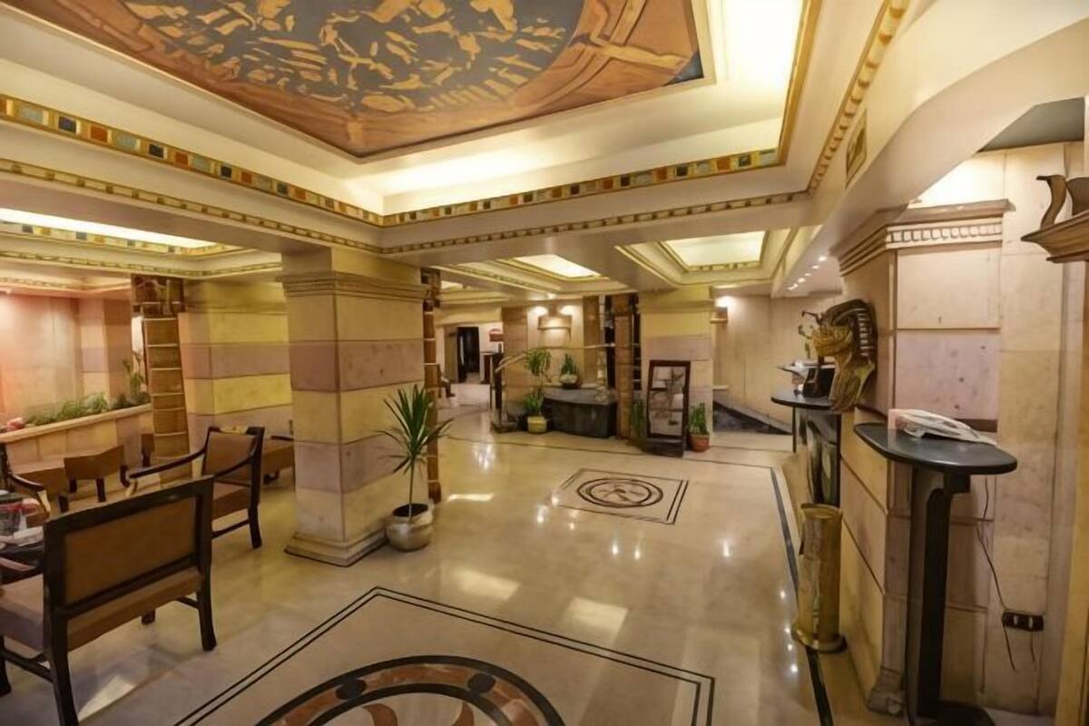 Eine geräumige Lobby mit hoher Decke, Marmorböden und einer zentralen Sitzgruppe mit Stühlen und Tischen.
