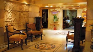 A lobby with stone-carved walls, a reception desk, and a large potted plant. - Zayed Hotel & Restaurant  (Giza)