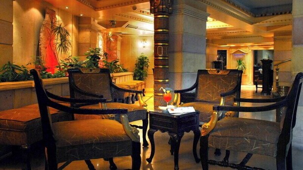 A lobby with ornate columns, plush seating, and a central table with a drink. - Zayed Hotel & Restaurant  (Giza)