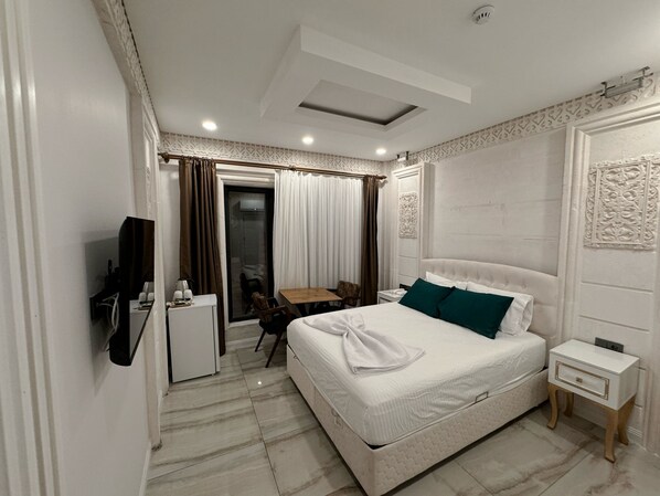 Een hotelkamer met een bed, een bureau, een stoel, een televisie en een deur naar een balkon.