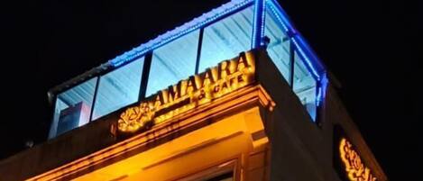 En byggnad med upplysta skyltar som visar texten "AMAARA" och "KONAL & CAFE".