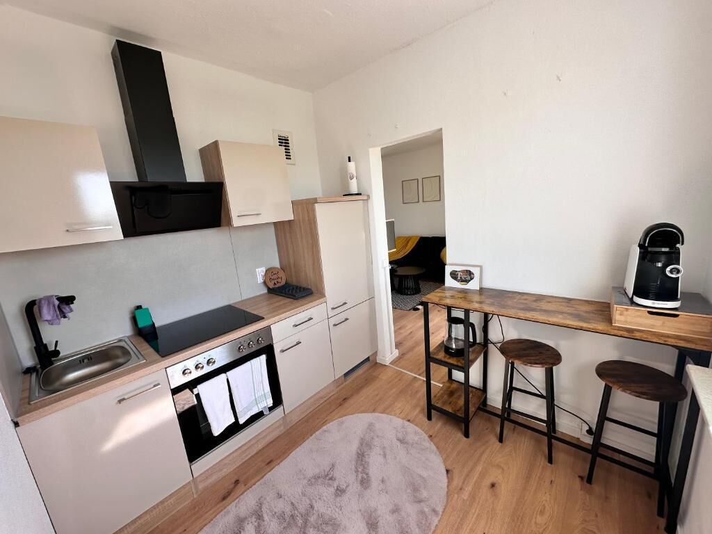 A compact kitchen with a stove, sink, and bar stools.