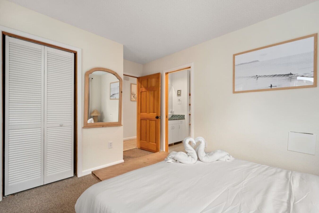 A bedroom with a bed, a wardrobe, a mirror, and a door leading to a bathroom.