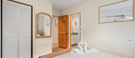 A bedroom with a bed, a wardrobe, a mirror, and a door leading to a bathroom.