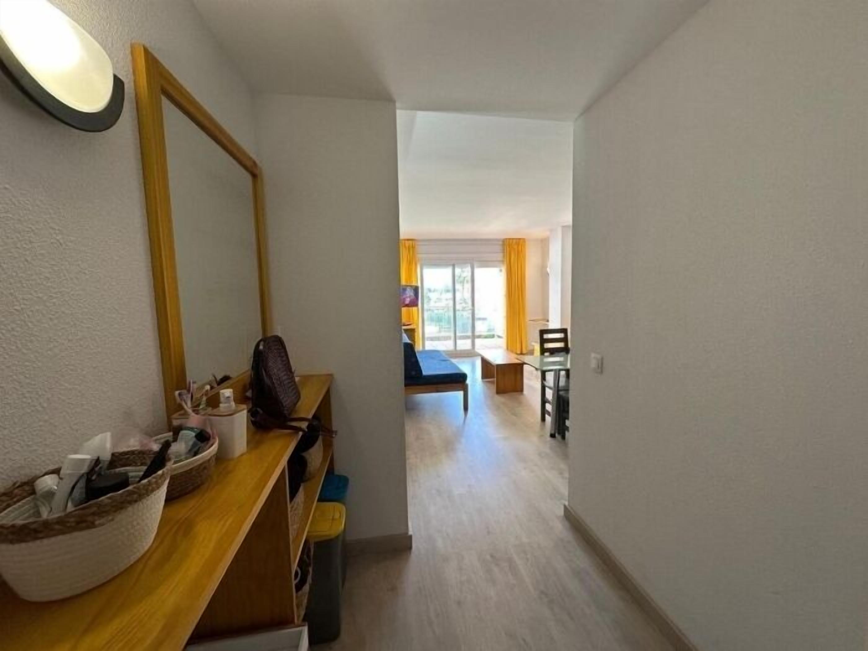 Ein schmaler Flur, der zu einem Schlafzimmer mit einem Bett, einem Schreibtisch und einem Stuhl führt.