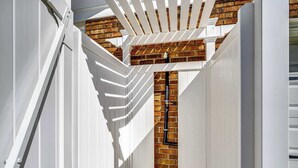 Un coin d’un bâtiment avec un revêtement extérieur blanc et un mur en briques.