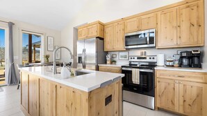 A modern kitchen with wooden cabinets, stainless steel appliances, and a central island. - Elk View-Access Elk River-Rural Acreage-Huge Patio (Noel)