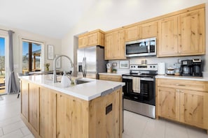 A modern kitchen with wooden cabinets, stainless steel appliances, and a central island.