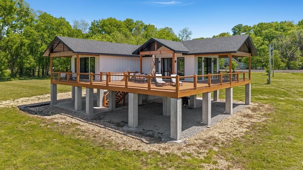 A two-story wooden structure with a deck, large windows, and a covered outdoor seating area. - Elk View-Access Elk River-Rural Acreage-Huge Patio (Noel)