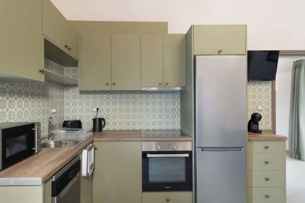 A compact kitchen with a microwave, oven, refrigerator, and a sink.