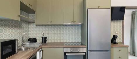 A compact kitchen with a microwave, oven, refrigerator, and a sink.