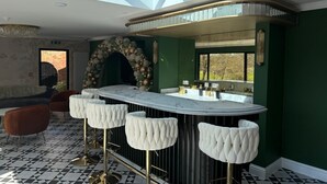 A modern kitchen with a bar area, featuring a marble countertop, bar stools, and a decorative arch. - The Mill Sharnbrook (Bedford)