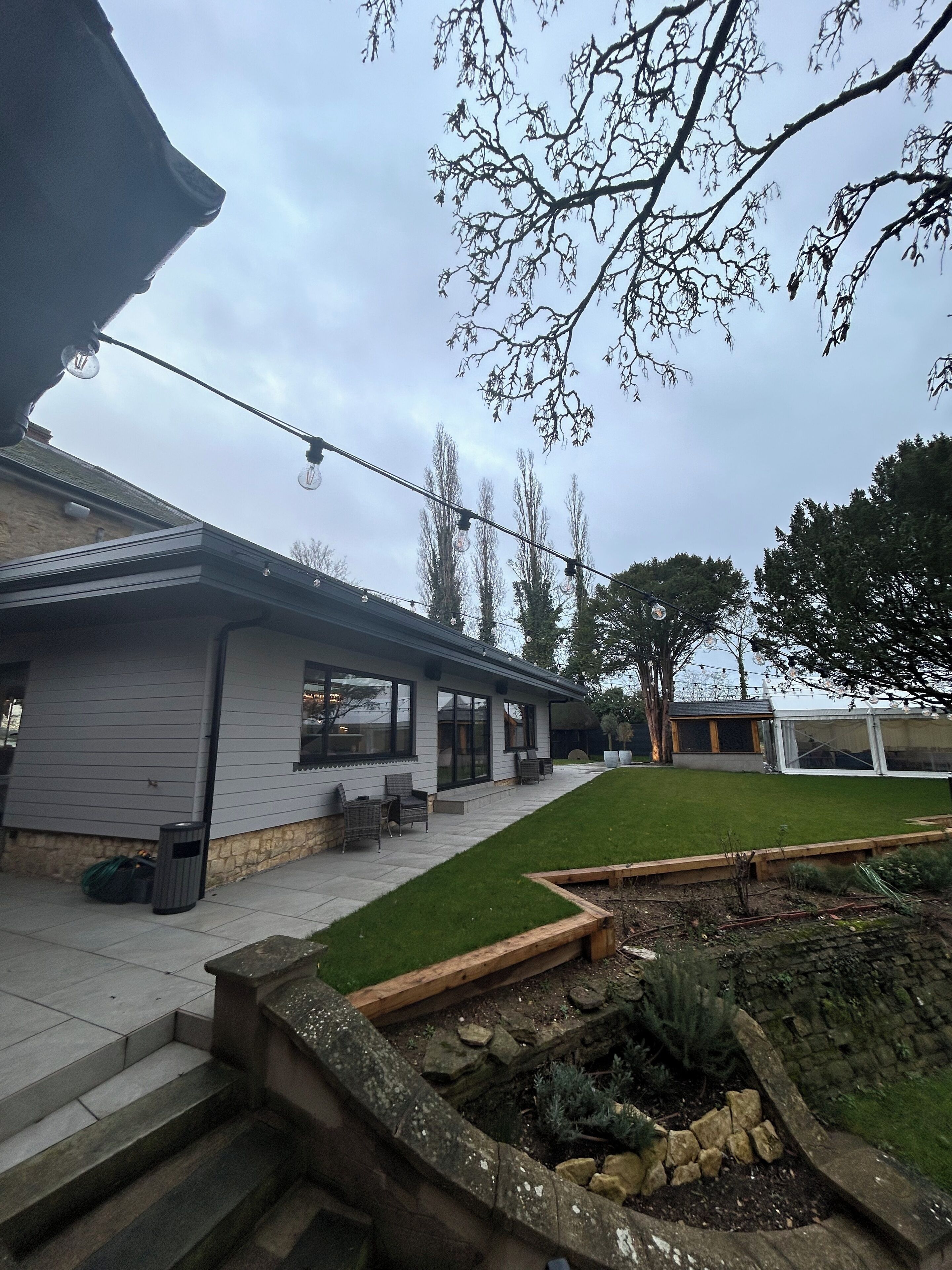 A modern house with a patio, a small garden, and a covered area.