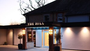 A building with a sign reading "THE MALL" at the entrance, featuring a modern design with a glass door and illuminated signage. - The Mill Sharnbrook (Bedford)