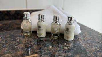 Four bottles of body lotion on a granite countertop in a bathroom.