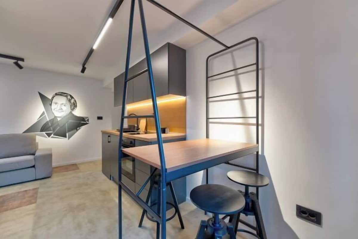 Una habitación moderna con escritorio, una silla, un sofá y un perchero en la pared.