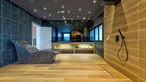 Une salle de spa moderne avec un fauteuil en mosaïque, un plancher en bois et un mur en bois intégrant une douche.
