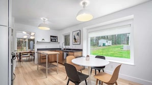 Una cocina moderna con comedor, ventanas amplias y vistas al exterior.