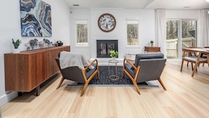 Una sala de estar con chimenea, dos sillones, una mesa de centro y un comedor con mesa y sillas de madera.