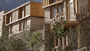 A mountain lodge with wooden balconies and stone walls, set against a backdrop of snow-capped peaks. - The Rihla Hunza - Managed By Luxus (Karimabad)
