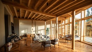 A spacious living area with wooden floors and large windows, featuring a sofa, chairs, and a coffee table. - The Rihla Hunza - Managed By Luxus (Karimabad)