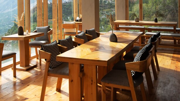 A wooden dining area with large windows overlooking a mountainous landscape. - The Rihla Hunza - Managed By Luxus (Karimabad)