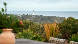 Une vue sur la côte, avec un phare, une végétation luxuriante et une terrasse en bois.