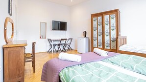 Un dormitorio con cama, escritorio, silla, televisor y armario.