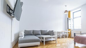 Una sala de estar moderna con un sofá modular, una mesita de centro blanca y una pequeña mesa de comedor con sillas.