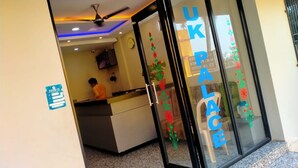 A reception area with a glass door marked 'UK PALACE,' a ceiling fan, and a clock on the wall. - DhamStay Hotel UK Palace Near Beach Puri (Puri)