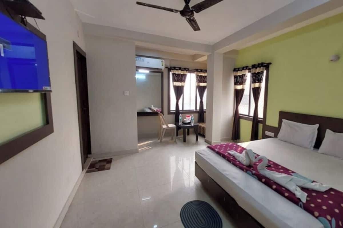 Una habitación de hotel con cama, escritorio, silla y ventilador de techo.