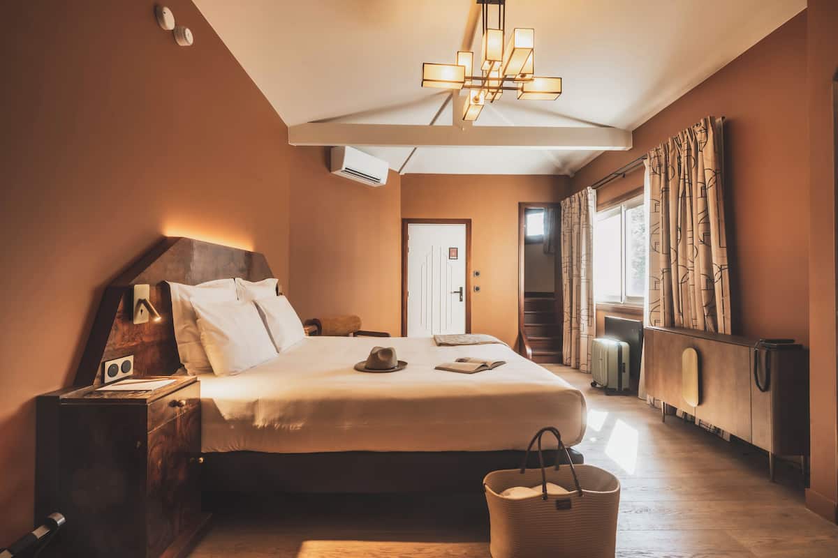 Un dormitorio con una cama grande, mesita de noche, lámpara y maleta.