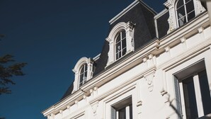 Un edificio clásico con fachada simétrica, múltiples ventanas y un balcón.