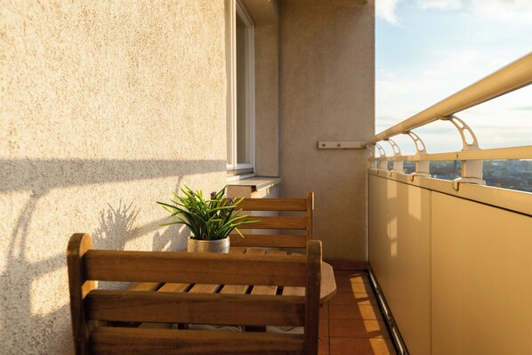 Un banco de madera con una planta en maceta en un balcón con vistas.