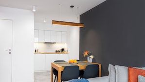 A modern kitchen with white cabinets, a wooden countertop, and a dining area with a table and chairs.
