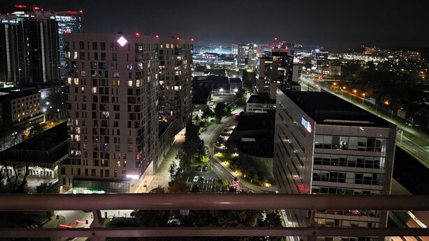 A nighttime cityscape with illuminated buildings and a busy street.