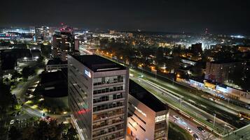 Un paisaje urbano nocturno con edificios modernos, una autopista de varios carriles y calles iluminadas.