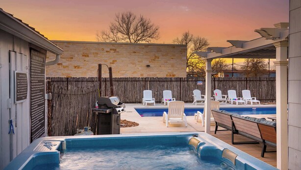 A backyard with a hot tub, lounge chairs, a barbecue grill, and a swimming pool. - Cosmopolitan- Hot Tub, Heated Pool & Fire Pit (Fredericksburg)