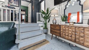 A staircase leading to a room with a television, a lamp, and a cabinet. - Cosmopolitan- Hot Tub, Heated Pool & Fire Pit (Fredericksburg)