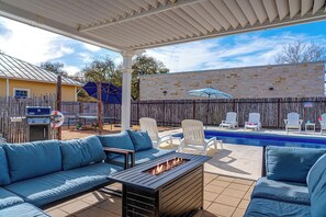 A covered patio with a pool, outdoor seating, and a barbecue area. - Cosmopolitan- Hot Tub, Heated Pool & Fire Pit (Fredericksburg)