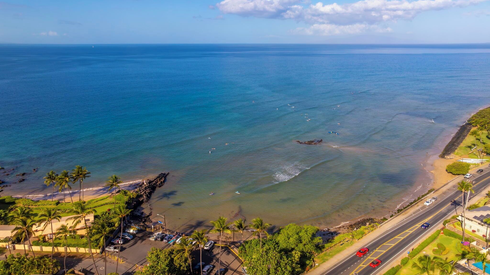 Una carretera costera con una playa a la derecha, palmeras y una vista despejada del océano.