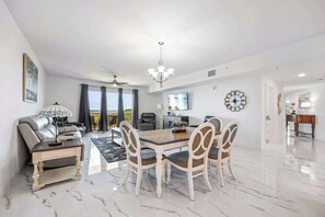 Un amplio salón con una mesa de comedor, sillas, un sofá y un ventilador de techo.