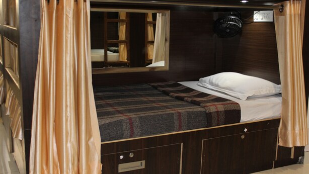 Une chambre à coucher de taille réduite, avec un lit simple, une fenêtre avec des rideaux, une petite table de chevet et une tête de lit.